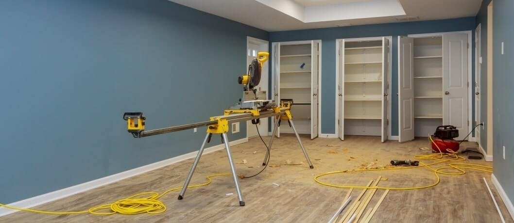 Renovated basement with new wood-look flooring, built-in shelves, and tools.