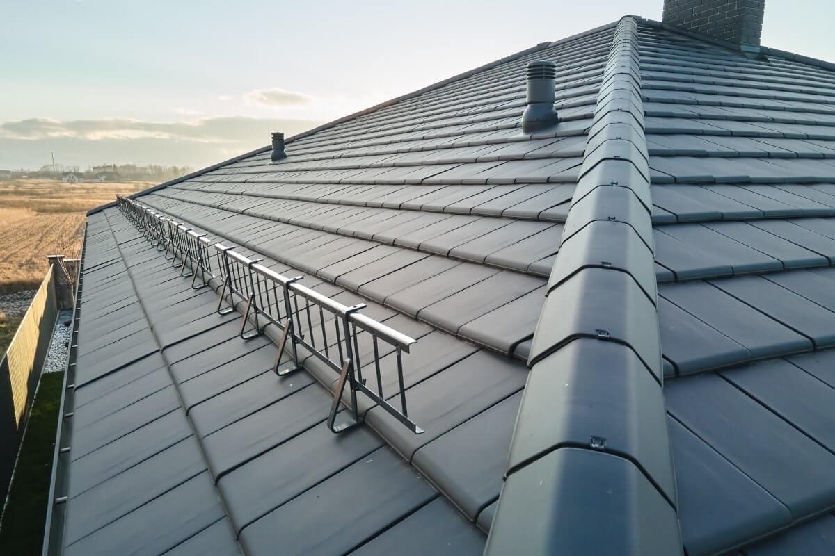 Dark tile roof with installed snow guards.