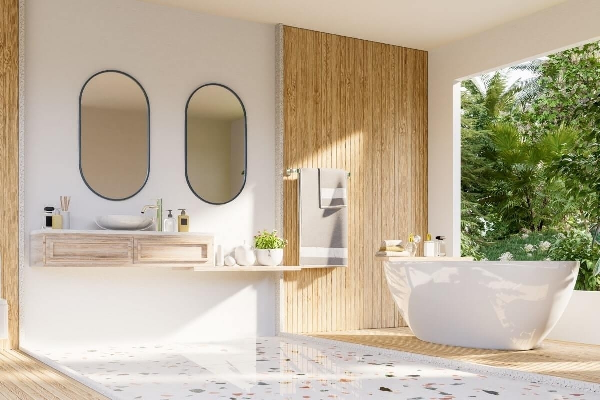 Bright, modern bathroom with terrazzo floor, wood vanity, and freestanding tub. Tropical view.